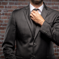Homem ajustando o botão do terno sob medida, simbolizando elegância e preparação para ocasiões especiais.