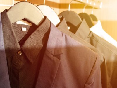 Roupas sociais penduradas em cabides dentro de um guarda-roupa.