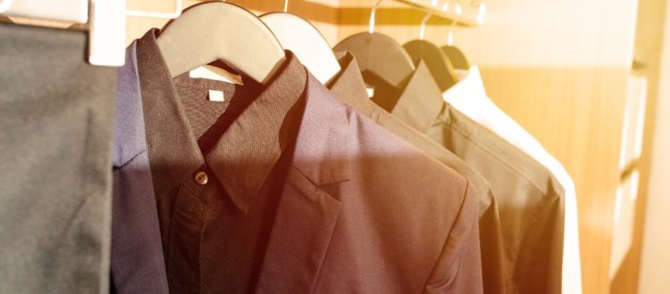 Roupas sociais penduradas em cabides dentro de um guarda-roupa.