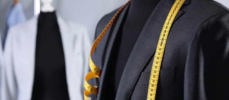 Blazer masculino em manequim com fita métrica sobre os ombros, representando alfaiataria e ajustes sob medida.