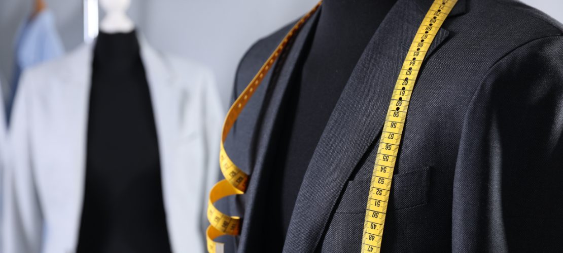 Blazer masculino em manequim com fita métrica sobre os ombros, representando alfaiataria e ajustes sob medida.